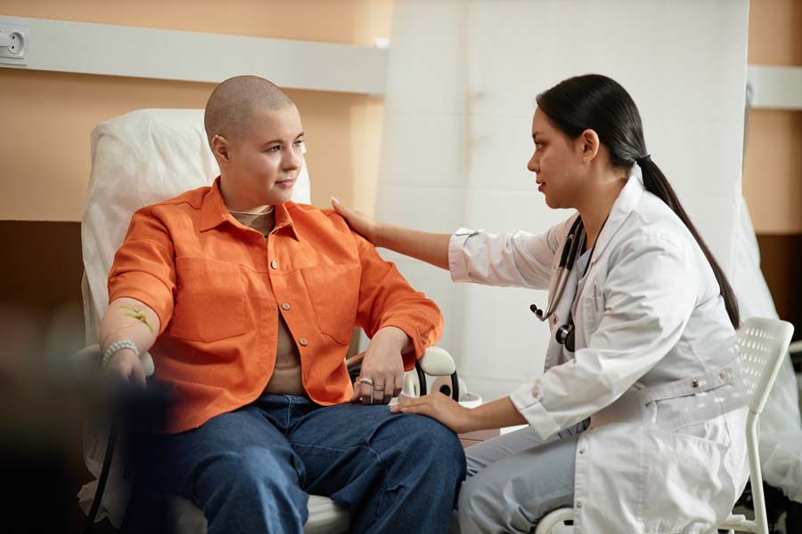 Cancer-Clinical-Trials-aim A person in a chair receiving treatment while being supported by a nursing support staff.