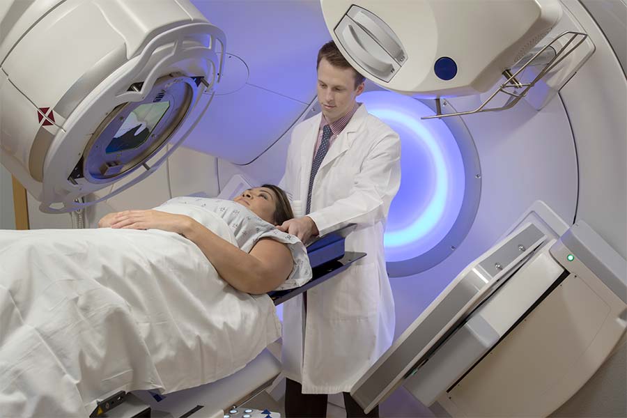 Clinical-Treatment A patient in a cancer treatment machine with technician behind the patient.
